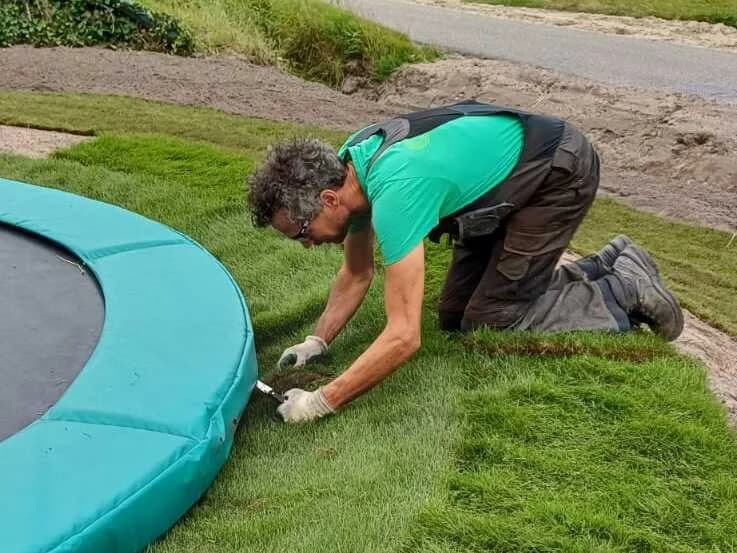 Johan legt graszoden en snijdt ze strak rond een trampoline
